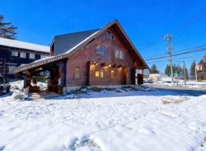 a large wooden building in the snow with snow at The Capsule Hakuba in Hakuba