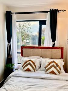 Un dormitorio con una cama con una ventana grande. en Zury Suites, en Nairobi
