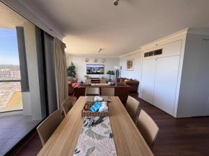 a room with a table and chairs and a living room at Canberra City View Apartment in Canberra
