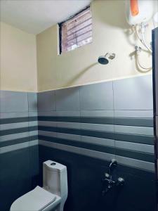 a bathroom with a white toilet and a window at Daya Dharmam Residency in Tiruvannāmalai