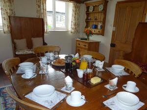 Una mesa de madera con platos y fuentes encima. en Glan Wye, en Rhayader