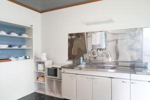 a kitchen with a sink and a microwave at ひだまりの宿 まゆしょう in Wada