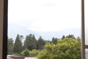 a window with a view of trees and mountains at ひだまりの宿 まゆしょう in Wada