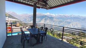 un tavolo e sedie su un balcone con vista sulle montagne di Rooftop Campsite Munsyari a Munsyari