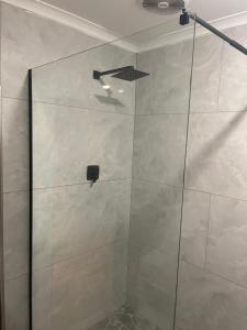 a shower with a glass door in a bathroom at Tucked away with a pool view in White River +4 photos