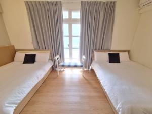 two beds in a room with a window at 宜蘭花境民宿 in Wujie