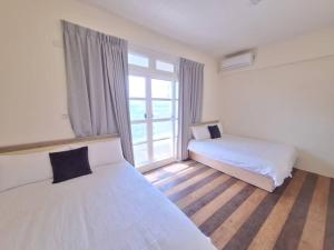 a bedroom with two beds and a window at 宜蘭花境民宿 in Wujie
