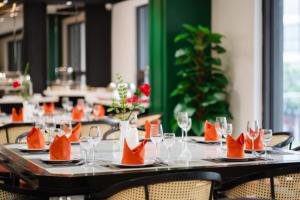 a table with orange napkins and wine glasses on it at MT Collection Hotel Ha Long in Ha Long