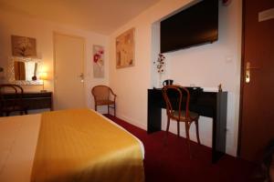 a hotel room with a bed and a desk with a television at Le Nouvel Hôtel du Théâtre in Paris