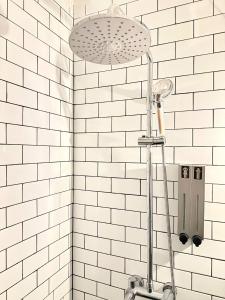 eine Dusche in einem Badezimmer mit weißen U-Bahn-Fliesen in der Unterkunft The Hammock Hotel Fine Arts Museum in Ho-Chi-Minh-Stadt