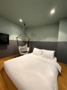 ein Schlafzimmer mit einem weißen Bett und einer hängenden Hängematte in der Unterkunft The Hammock Hotel Fine Arts Museum in Ho-Chi-Minh-Stadt