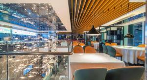 ウルムチ市にあるUrumqi Bayinhe Hotelのテーブルと椅子とガラス窓のあるレストラン