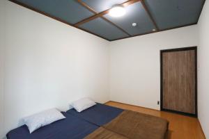 a bedroom with a bed and a door at ひだまりの宿 まゆしょう in Omachi