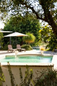une piscine avec deux chaises et un parasol dans l'établissement 18Th Century Farmhouse In Racalmuto Countryside, à Grotte