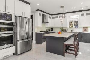 a kitchen with white cabinets and stainless steel appliances at 8BR New Spacious Home White Rock HVAC Free Parking in Surrey