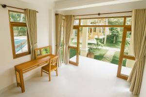 a living room with a bench and large windows at Coconut Garden Mui Ne in Mui Ne
