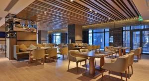 een restaurant met tafels, stoelen en ramen bij Zhejiang Cloud Mountain Deefly Hotel in Penshan