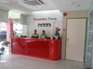 deux personnes assises à un comptoir rouge dans un magasin dans l'établissement Hotel Strawberry Fields, à Petaling Jaya