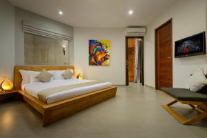 a bedroom with a large bed and a chair at Villa Miro in Seminyak