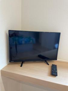a television sitting on a table with a remote control at ゲストハウス坂の上のソルティーズ in Kainan