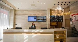 Eine Frau, die an einem Tresen in einer Lobby sitzt. in der Unterkunft City Comfort Inn Fuyang Hongqi Middle School Erlijing Night Market in Fuyang