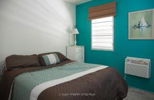 a bedroom with a bed with blue walls and a window at Safe Quiet Apartments Near Airport in Carolina