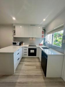 a kitchen with white cabinets and a sink at The Lazy Break at Trinity in Trinity Beach
