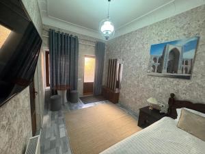 a bedroom with a bed and a flat screen tv at Hotel Ravshan Boutique in Bukhara