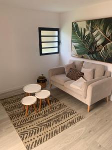 Una sala de estar con un sofá y dos mesas. en L horizon, en Ravine des Cabris