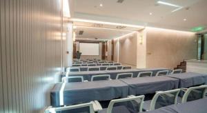 a conference room with rows of chairs and a screen at Tomeet Hotel in Meizhou
