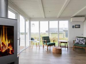 Torstedにある6 person holiday home in Thistedのリビングルーム(暖炉、ソファ、椅子付)