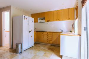 a kitchen with a white refrigerator and wooden cabinets at The Princess House in Prevelly