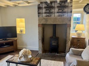 ein Wohnzimmer mit einem Kamin, einem Sofa und einem TV in der Unterkunft Coupling Cottage in Belper