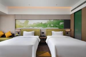 twee bedden in een kamer met een schilderij aan de muur bij Hilton Garden Inn Chengde Mountain Resort in Niuquanzigou