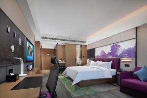 een slaapkamer met een groot wit bed en een paarse bank bij Hilton Garden Inn Chengde Mountain Resort in Niuquanzigou