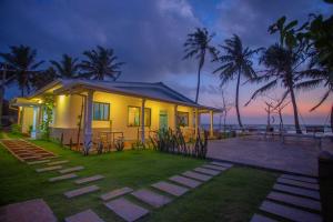 a small yellow house with palm trees and the ocean at Villa Amor by the Beach in Ambalangoda