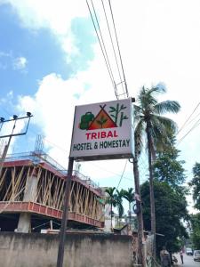ein Schild für ein Hotel vor einem Gebäude in der Unterkunft Tribal Hostel & Homestay in Guwahati