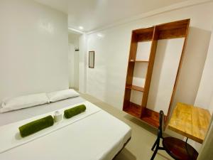 Un dormitorio con una cama blanca y un espejo. en Laguno Hostel and Guest House, en Moalboal
