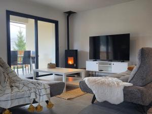 a living room with two chairs and a flat screen tv at Le chalet du Petit Ours Brun in Formiguères