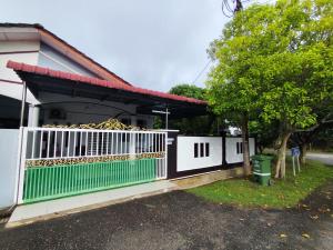 a house with a white gate and a tree at AHA Homestay Temerloh with 3 bedrooms, 2 toilet in Temerloh