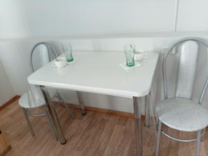 a white table with two chairs and two vases on it at Мотель 32 in Aktobe