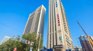 two tall buildings in a city with a blue sky at 7 Days Inn Harbin West Railway Station in Harbin