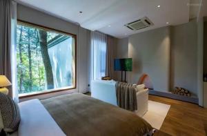 Un dormitorio con una cama grande y una ventana grande en Huangshan Xishui Yunjian Forest Resort Hotel, en Huangshan