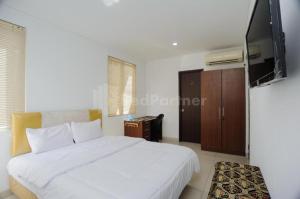 a bedroom with a white bed and a flat screen tv at Green Residence 25 Syariah Karawaci RedPartner in Binong