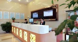 Dos mujeres sentadas en un mostrador de recepción en un vestíbulo en GreenTree Inn Taizhou Gaogang District Business Hotel, en Sixiang