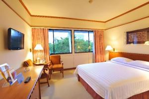 スラバヤにあるElmi Hotelのベッドと机と窓があるホテルの部屋