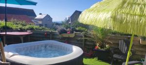 AudervilleにあるChambre phareの庭に藁傘のある温水浴槽