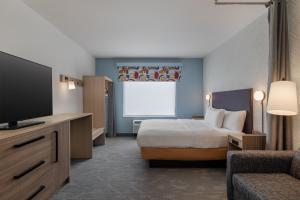 una habitación de hotel con cama y televisor de pantalla plana en Home2 Suites By Hilton Ames, en Ames