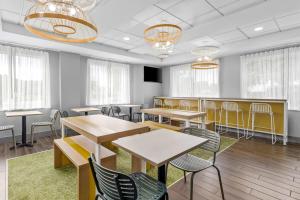 a dining room with tables and chairs and windows at Spark by Hilton Lynchburg in Lynchburg