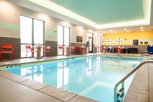 a large swimming pool with red chairs and tables at Tru By Hilton Grimes Des Moines in Grimes